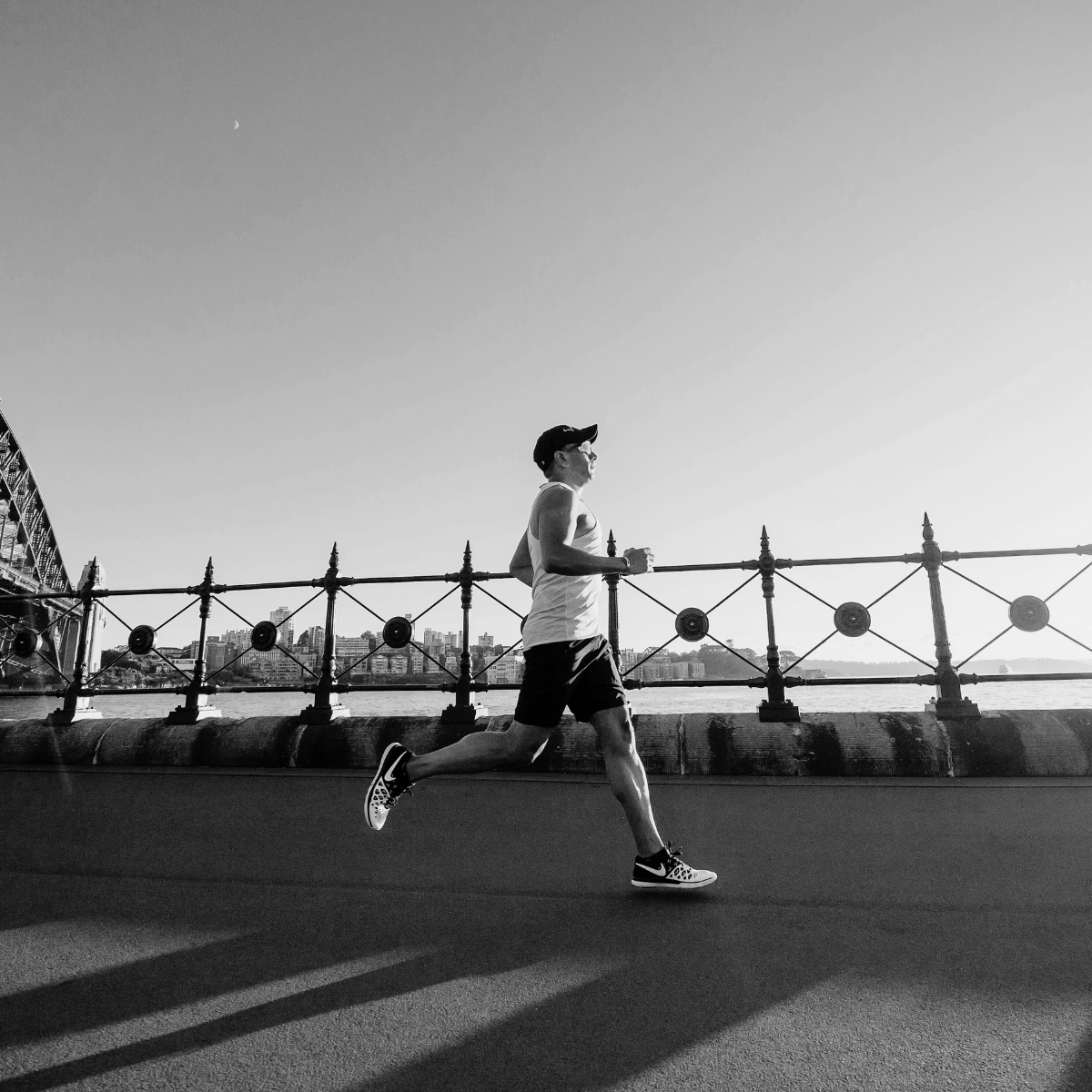 Person running on a path with a bridge and cityscape in the background