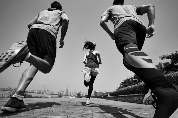 Three people running on a path with a city skyline in the background